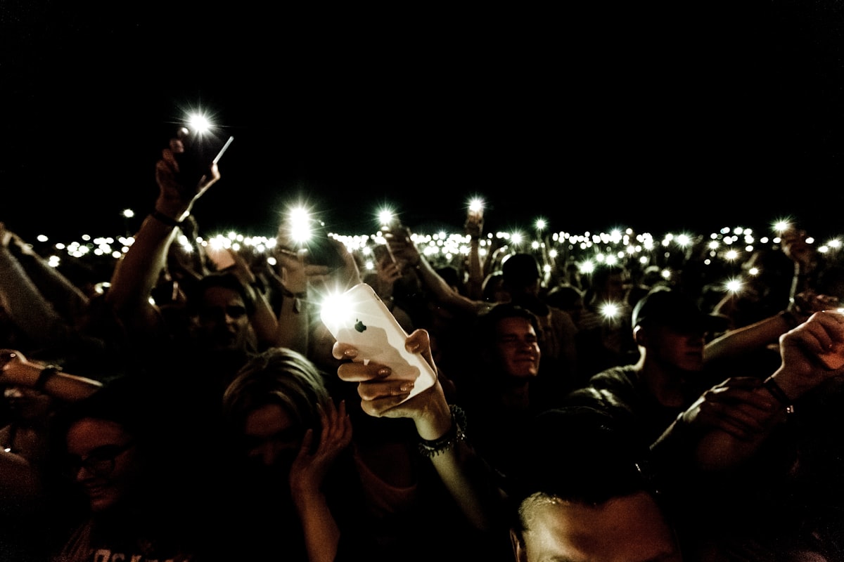 A sea of phone screens glowing in darkness